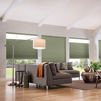 bright modern living room with light grey couch, pastel green window coverings