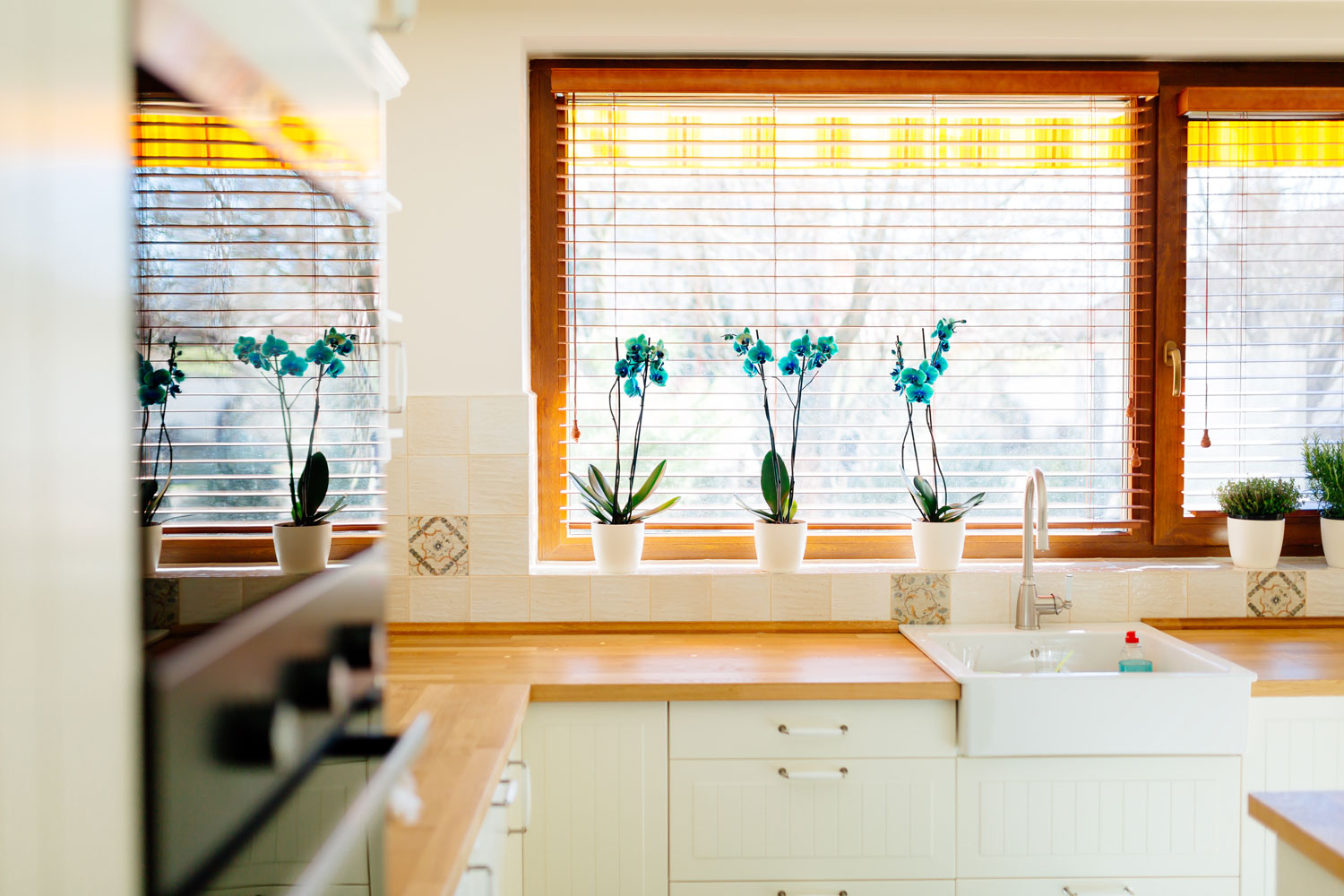 A bright modern kitchen with warm orange colour blinds and overlooking the frontyard